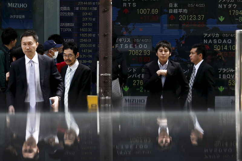 © Reuters. FILE PHOTO: People walk in front of board displaying stock indexes  in Tokyo