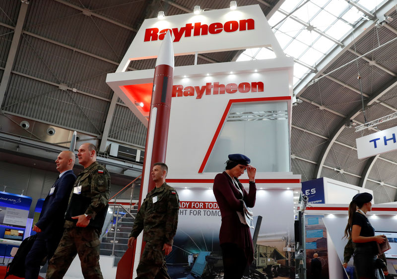 © Reuters. People pass the U.S. defense company Raytheon stand at an international military fair in Kielce