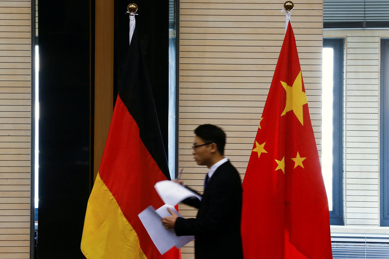 © Reuters. Un hombre pasa frente a las banderas nacionales de China y Alemania antes de una reunión de altos cargos entre los respectivos ministerios de comercio y economía en Pekín