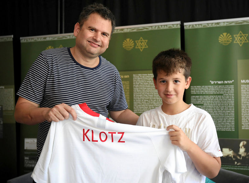 © Reuters. Yoav Dekel and his son, relatives of former football player Jozef Klotz, hold a football shirt during an event to remember Polish Jewish footbal legends in Warsaw