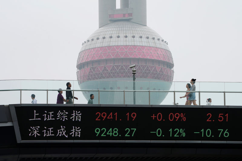 © Reuters. People walk by an electronic board showing the Shanghai and Shenzhen stock indexes, on a pedestrian overpass at Lujiazui financial district in Shanghai