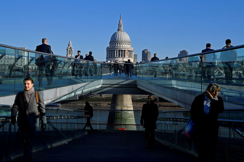 © Reuters. FILE PHOTO: Workers are seen crossing the Millennium Bridge, with St Paul's Cathedral seen behind during the morning rush hour in London