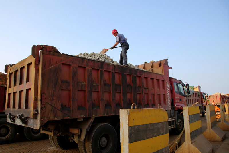 © Reuters. A man works on transporting iron ore on a truck at Ganyu port in Lianyungang