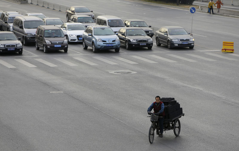 © Reuters. A man rides a tricycle past vehicles through a junction in Beijing