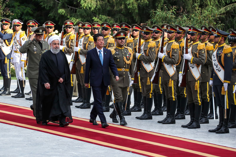 © Reuters. Iranian President Hassan Rouhani walks with Japan's Prime Minister Shinzo Abe, during a welcome ceremony in Tehran