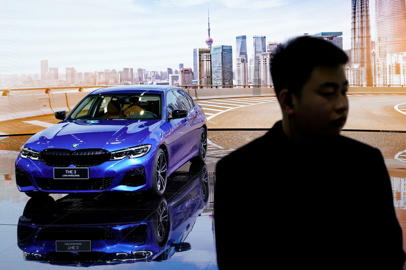 © Reuters. Man stands in front of a BMW 3 Series Long Wheelbase (LWB) car presented during the media day for Shanghai auto show