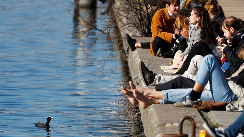 © Reuters. Un grupo de personas toma sol a la orilla del río Spree cerca de la Side Gallery en Berlín. Foto de archivo. Febrero, 2019. REUTERS/Fabrizio Bensch