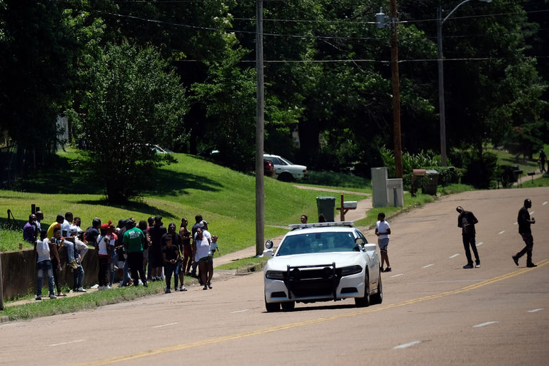 © Reuters. A police car drives by a group of people the day after violent clashes between police and protesters broke out on streets overnight in Memphis