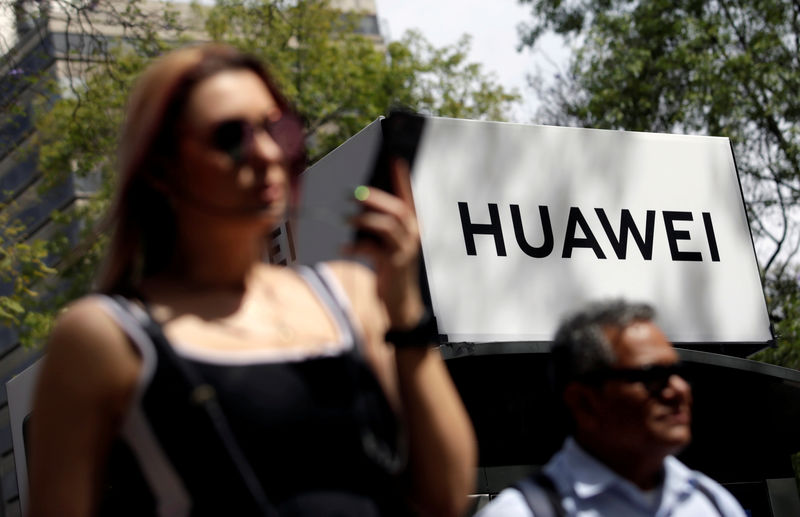© Reuters. IMAGEN DE ARCHIVO: Gente pasa frente a un logo de Huawei en una para de buses en Ciudad de México.