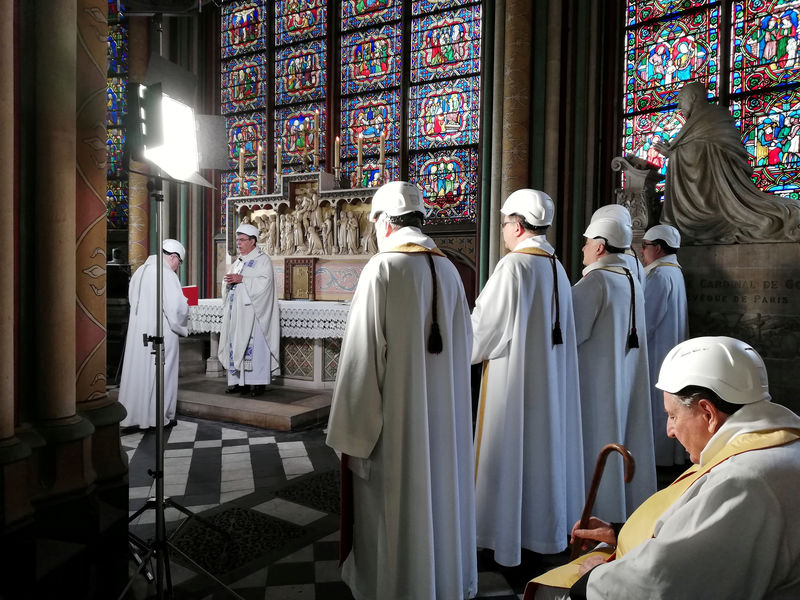 © Reuters. مصلون يرتدون الخوذ يحضرون أول قداس في كاتدرائية نوتردام منذ الحريق