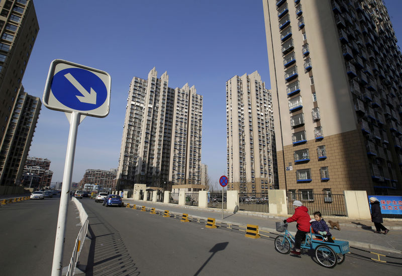 © Reuters. Una mujer lleva un niño en un triciclo cerca de un complejo residencial en el distrito de Tongzhou de Pekín