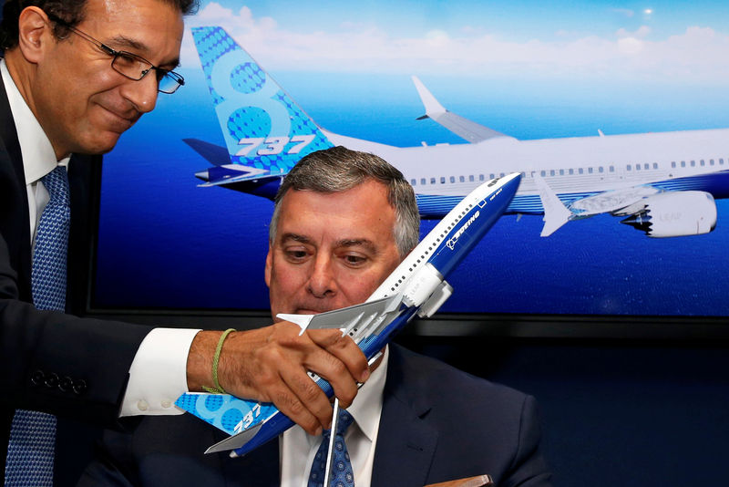 © Reuters. Ihssane Mounir holds a model of a Boeing 737 MAX in front of Kevin McAllister, Boeing Commercial Airplanes CEO, during a commercial announcement at the 53rd International Paris Air Show at Le Bourget Airport near Paris