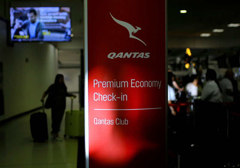 © Reuters. FILE PHOTO: A passenger walks with their luggage as they approach a Qantas Airways check-in counter at Sydney International Airport