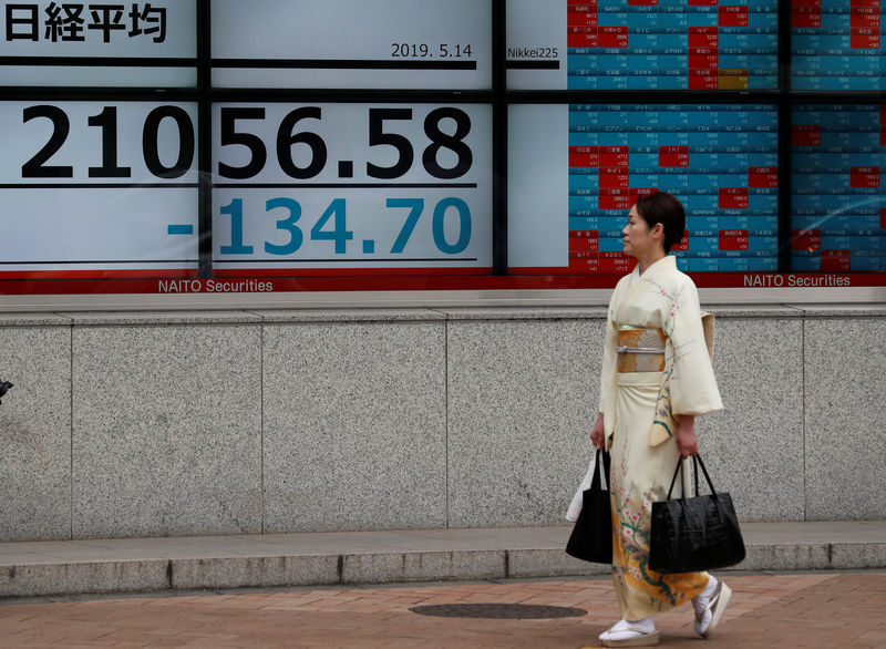 © Reuters. Una donna in kimono cammina davanti a un tabellone elettronico che mostra il Nikkei stock index fuori dalla Borsa di Tokyo