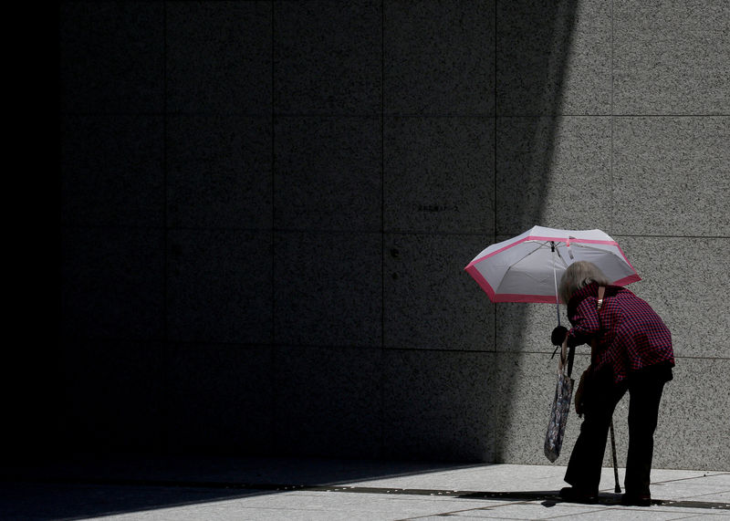 © Reuters. FILE PHOTO : A woman carrying a parasol makes her way into a commercial building in Tokyo