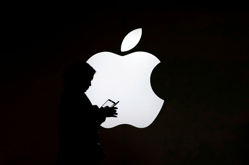 © Reuters. FILE PHOTO: A woman looks at the screen of her mobile phone in front of an Apple logo outside its store in Shanghai
