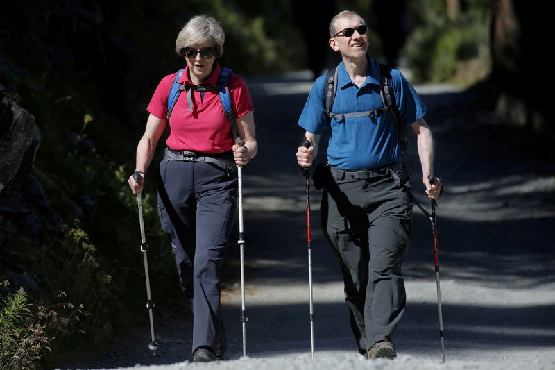 © Reuters. FILE PHOTO: Britain's Prime Minister Theresa May walks in a forest with her husband Philip at the start of a summer holiday in the Alps, in Switzerland