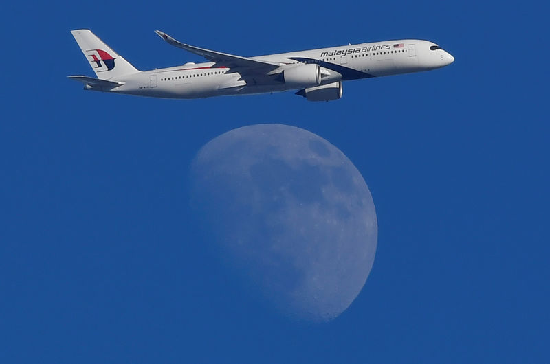 © Reuters. A Malaysian Airlines passenger aircraft is seen flying in front of the moon, over London, Britain