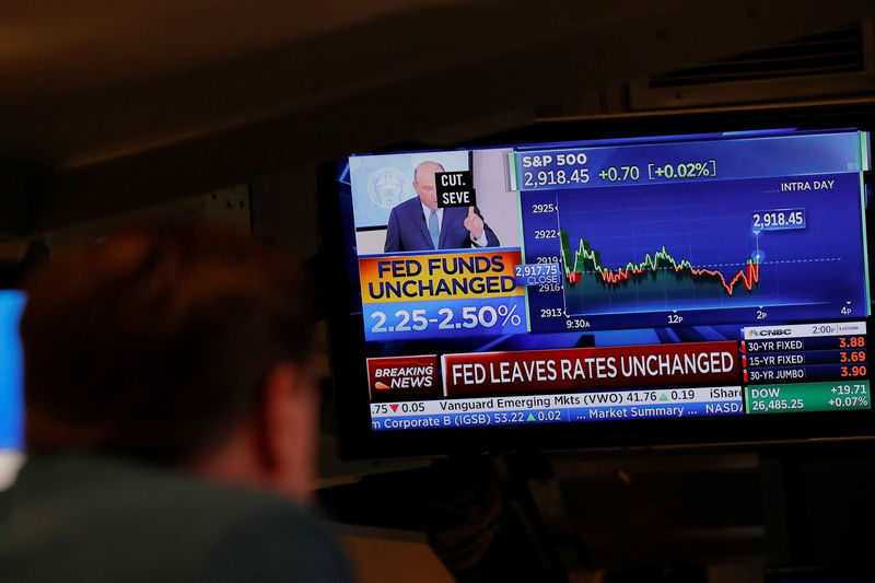 © Reuters. A trader looks at a screen as a television announces that the Fed rate will remain unchanged on the floor of the New York Stock Exchange in New York