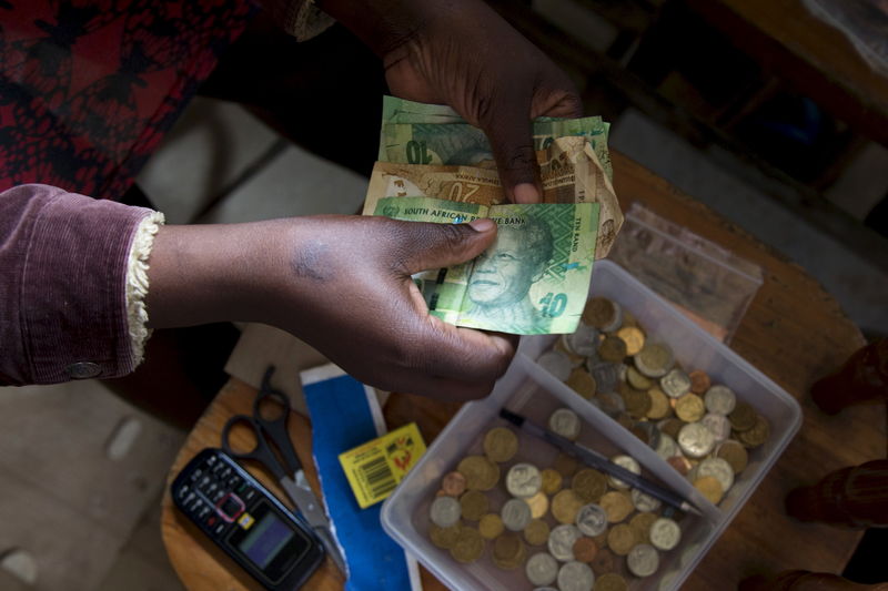 © Reuters. A shopkeeper counts out change above her cash box at her shop in Hillcrest, west of Durban