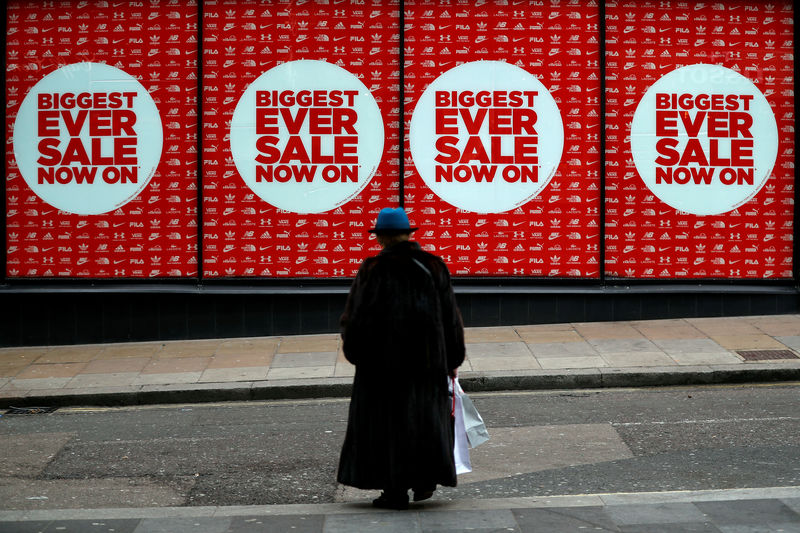 © Reuters. FILE PHOTO: A pedestrian walks towards a shop displaying a sale sign, in central London