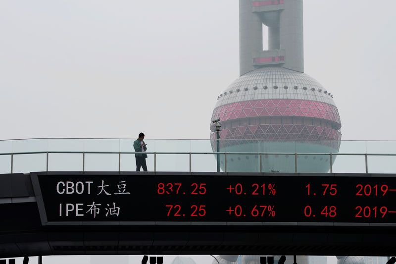 © Reuters. Man uses his phone above an electronic board showing the CBOT soybean futures on a pedestrian overpass at Lujiazui financial district in Shanghai