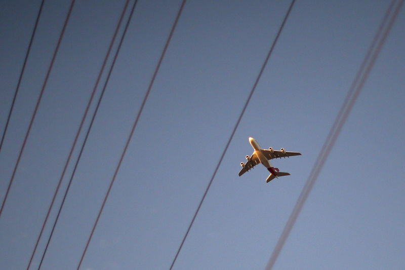 © Reuters. FILE PHOTO:  A plane flies towards the rising sun behind power lines in Los Angeles