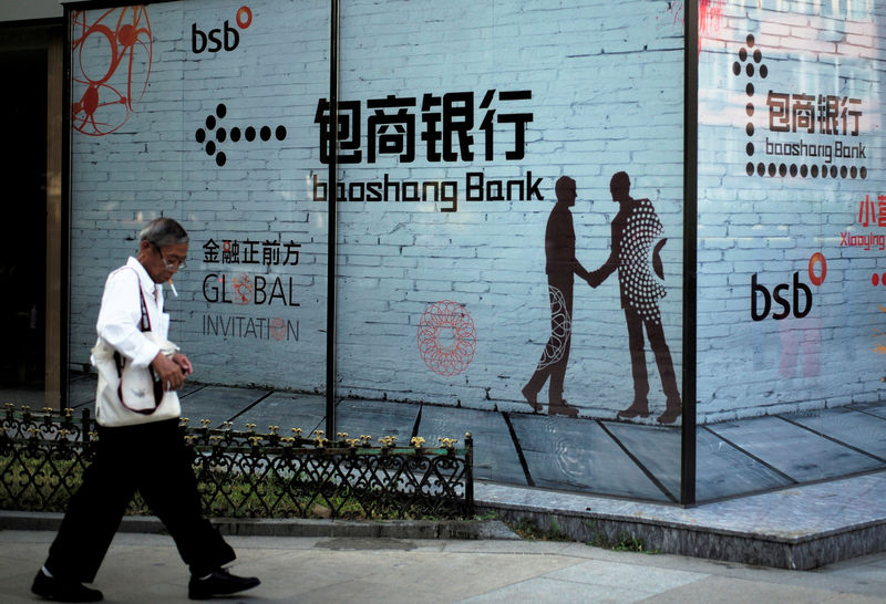 © Reuters. FILE PHOTO: Man walks past a building with an advertisement of Baoshang Bank in Beijing