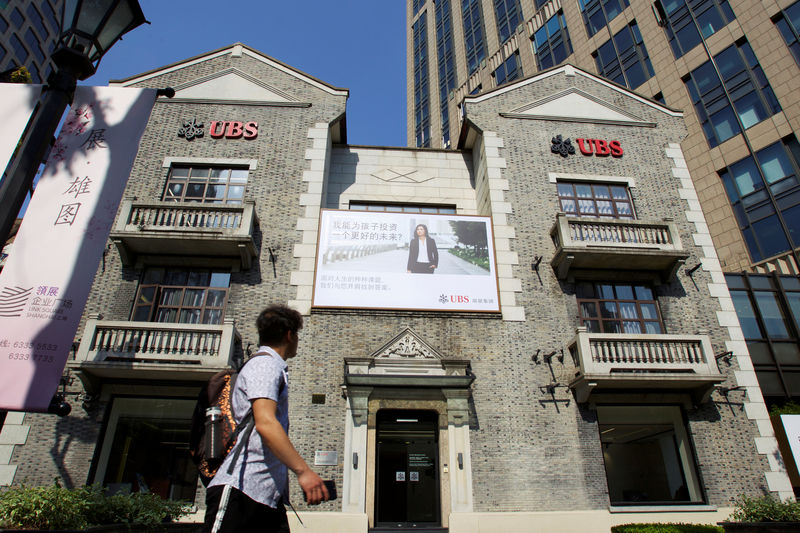 © Reuters. FILE PHOTO: Man walks past a building of Swiss bank UBS in Shanghai