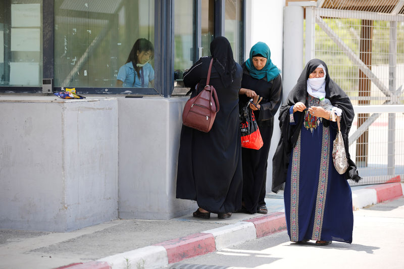 © Reuters. Palestinian women stand next to the counter of an Israeli official at the Israeli side of Erez crossing, on the border with Gaza