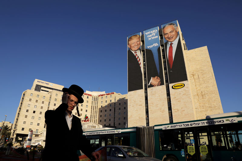 © Reuters. Un hombre pasa junto a un cartel de la campaña electoral del Likud en Jerusalén, en la que el presidente de Estados Unidos, Donald Trump, estrecha la mano del primer ministro israelí, Benjamin Netanyahu