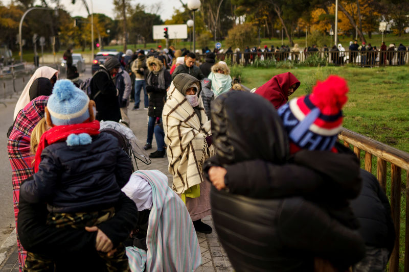 © Reuters. Grupo de personas haciendo cola para solicitar asilo frente a una comisaría de policía en Madrid