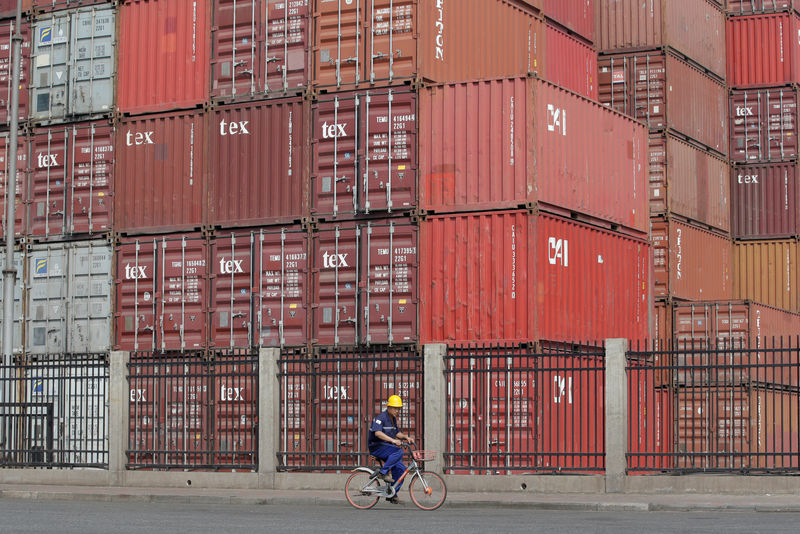 © Reuters. FILE PHOTO: A worker cycles past containers outside a logistics center near Tianjin Port