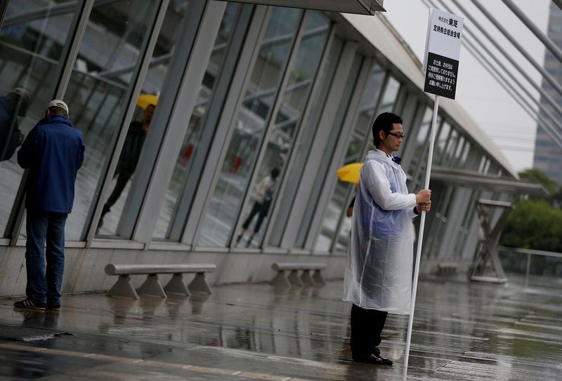 © Reuters. FILE PHOTO: A staff member of Toshiba Corp. holds a sign board of the company's annual shareholders meeting at an entrance of the venue in Chiba, Japan