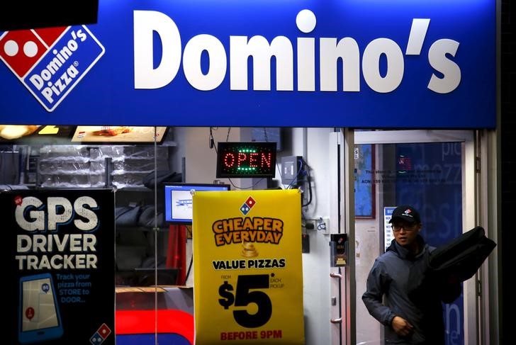 © Reuters. FILE PHOTO: A worker carries a pizza for delivery as he exits a Domino's pizza store in Sydney, Australia