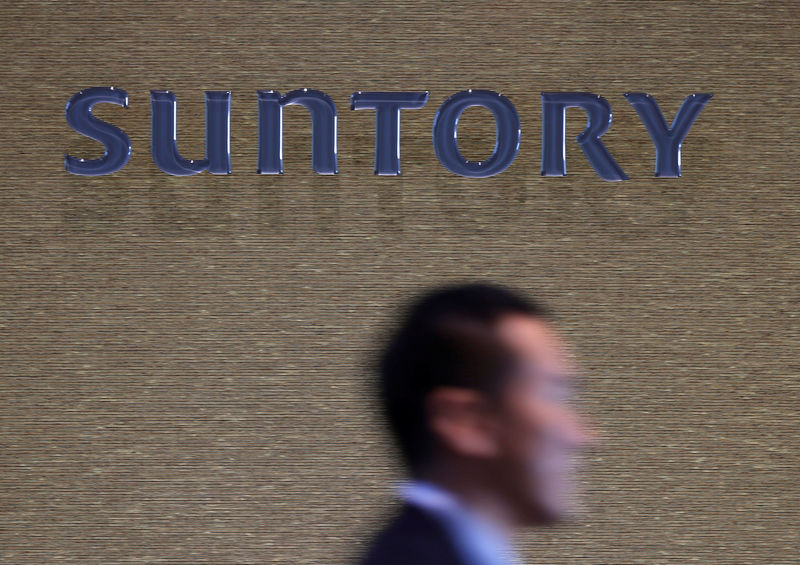 © Reuters. FILE PHOTO: Man walks past a signboard of Suntory Holdings at the entrance of Suntory World Headquarters in Tokyo