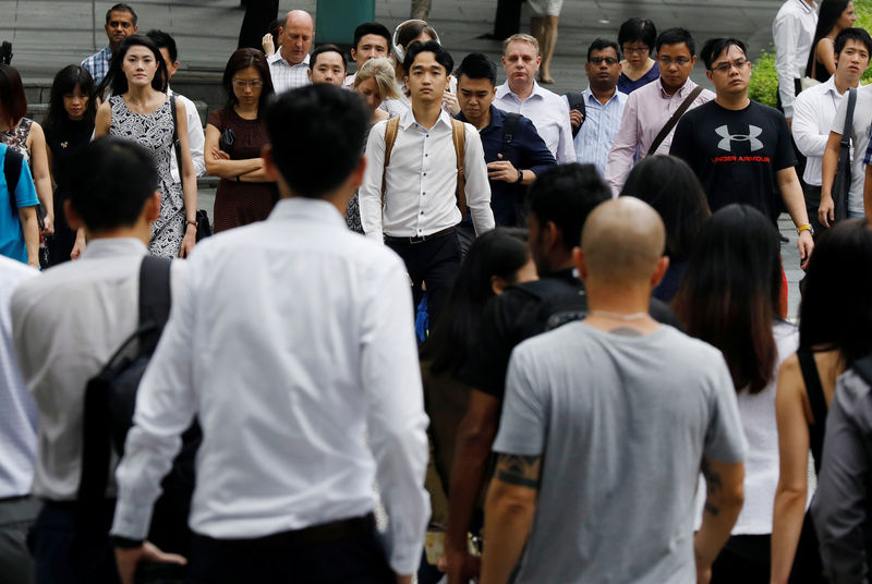 © Reuters. FILE PHOTO: Office workers cross a street in Singapore's central business district