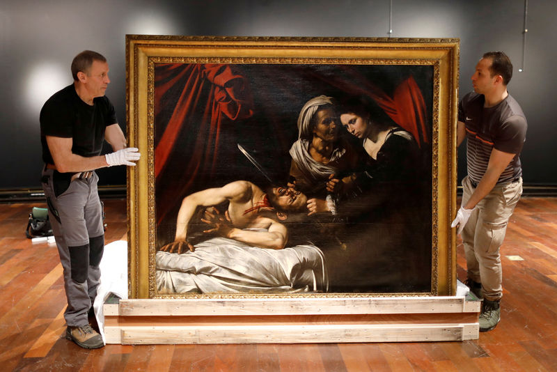 © Reuters. FOTO DE ARCHIVO: Operarios sujetando el cuadro titulado "Judith decapitando a Holofernes", atribuido al maestro italiano Caravaggio, en la casa de subastas Drouot de París