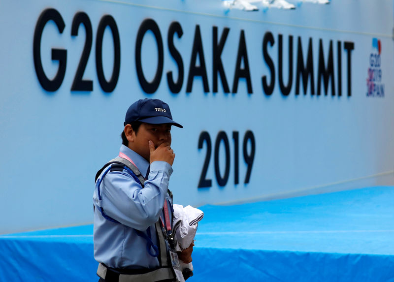 © Reuters. Agente de segurança caminha em frente a painel com logo de cúpula do G20 em Osaka, Japão