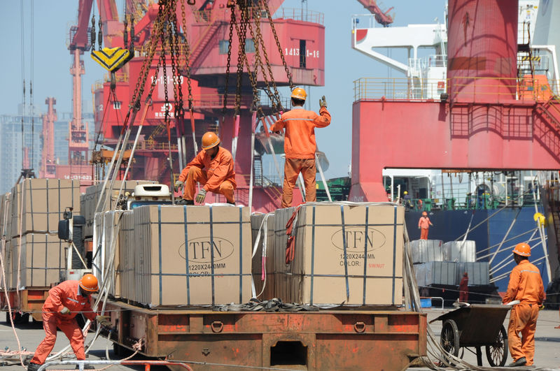 © Reuters. FILE PHOTO: Workers load goods for export onto a crane at a port in Lianyungang