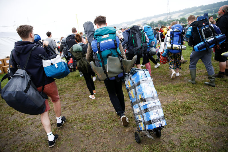 © Reuters. Gente llevando sus posesiones cuando llega al Festival de Glastonbury en la granja Worthy en Somerset, Reino Unido