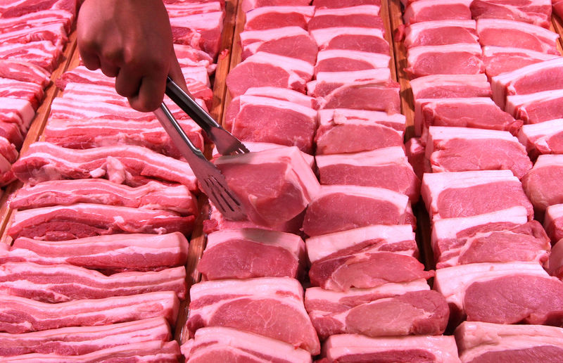 © Reuters. Staff member lifts a pork slice with tongs at a supermarket in Handan, Hebei