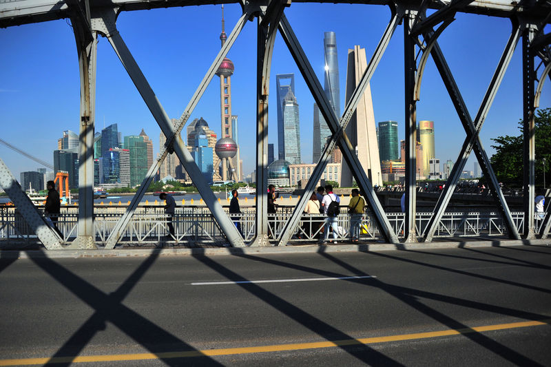 © Reuters. FILE PHOTO: People walk on a bridge near the financial district of Pudong in Shanghai