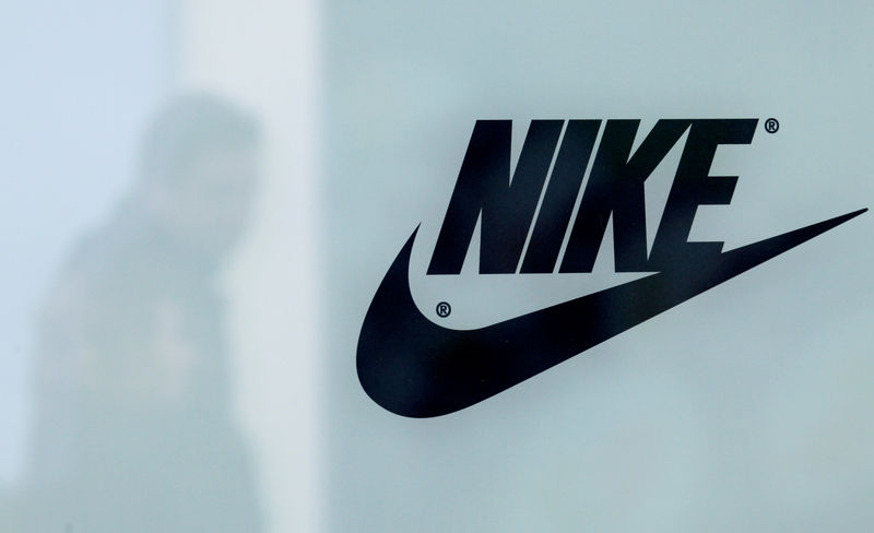 © Reuters. FILE PHOTO: A customer is reflected in a shop window decorated with Nike store logo at the outlet village Belaya Dacha outside Moscow