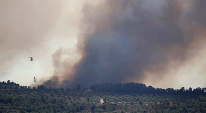 © Reuters. Un helicóptero deja caer agua durante un incendio forestal cerca de Bovera, Tarragona, España.