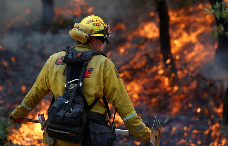 © Reuters. Firefighters work to defend homes from an approaching wildfire in Sonoma, California