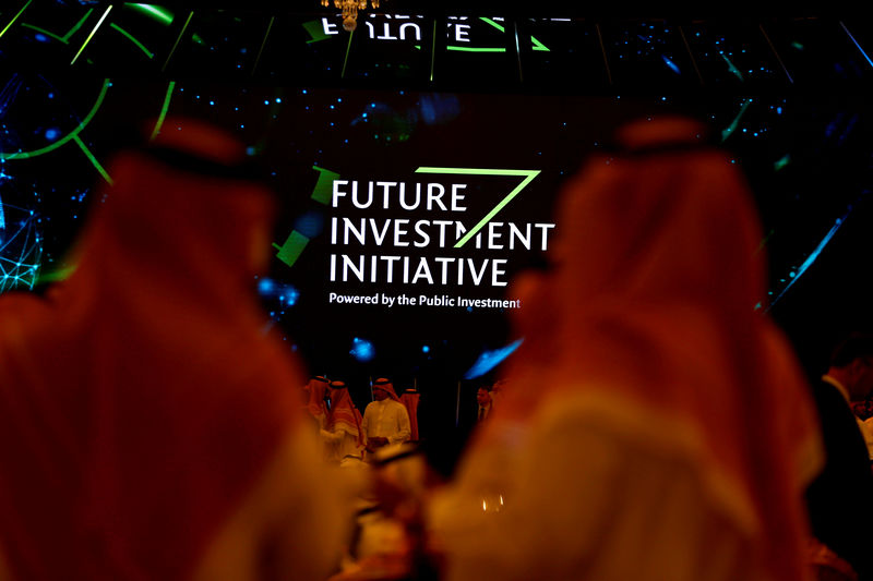 © Reuters. FILE PHOTO: Participants look at a sign of the Future Investment Initiative during the investment conference in Riyadh