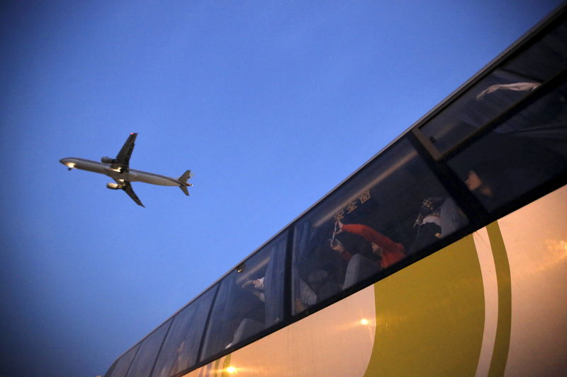 © Reuters. People on a bus look at an airplane as it lands at Hongqiao International Airport in Shanghai