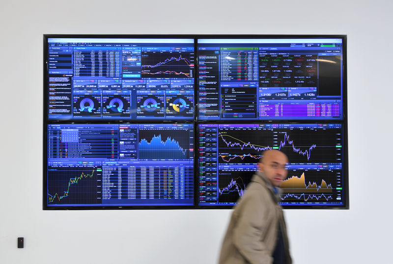 © Reuters. FILE PHOTO: A man walks past a screen displaying share prices at CMC Markets in London