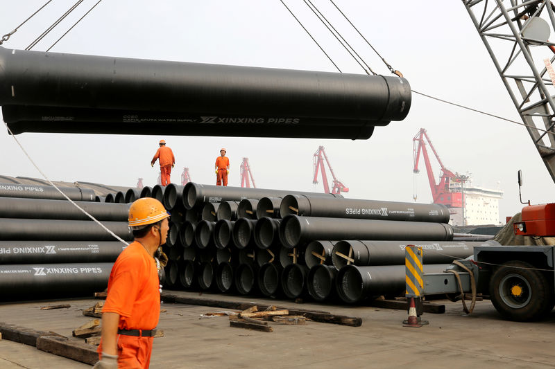 © Reuters. Workers direct a crane lifting steel pipes for export at a port in Lianyungang, Jiangsu